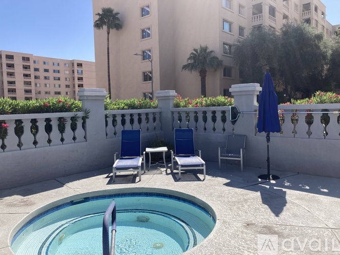 A pool with chairs and a table is surrounded by a white fence.
