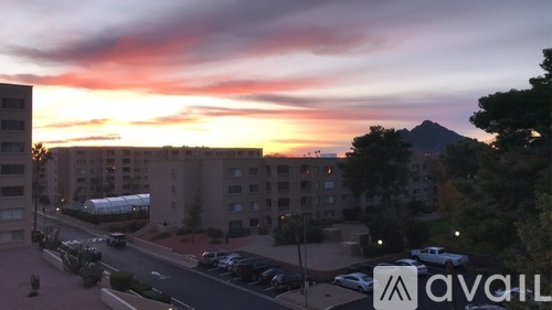 A sunset view of a parking lot with cars and buildings.