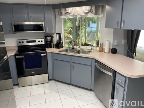 A kitchen with a stove, sink, and cabinets.