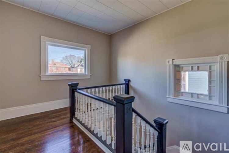 A room with a window and a balcony with a railing.