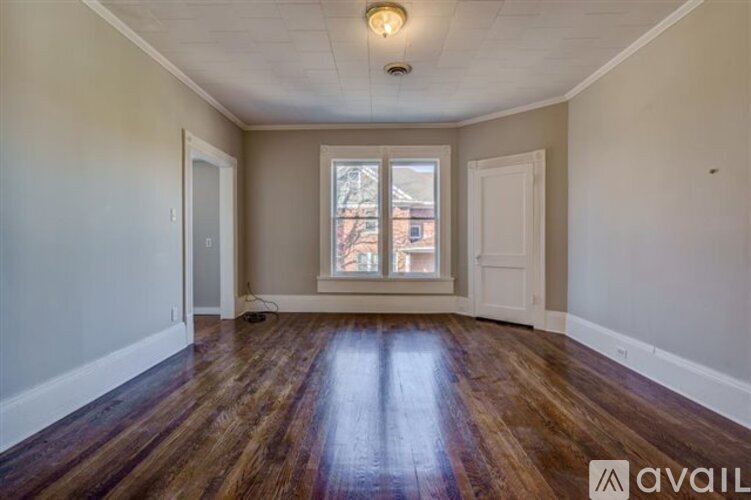A room with wooden floors and a window showing a view of a building outside.