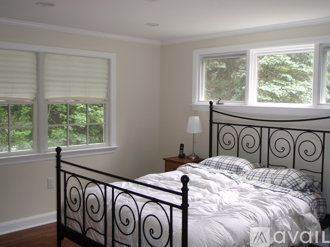 A bedroom with a large bed and a window with blinds.