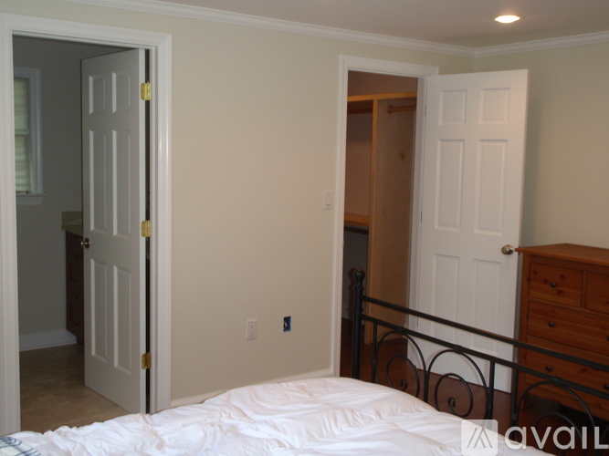 A bedroom with a bed, dresser, and two doors.