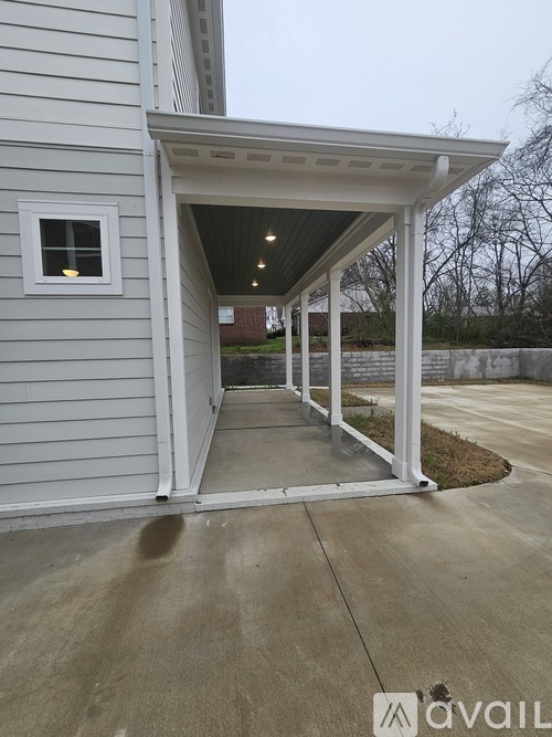 A covered walkway leads to a building with a white door.