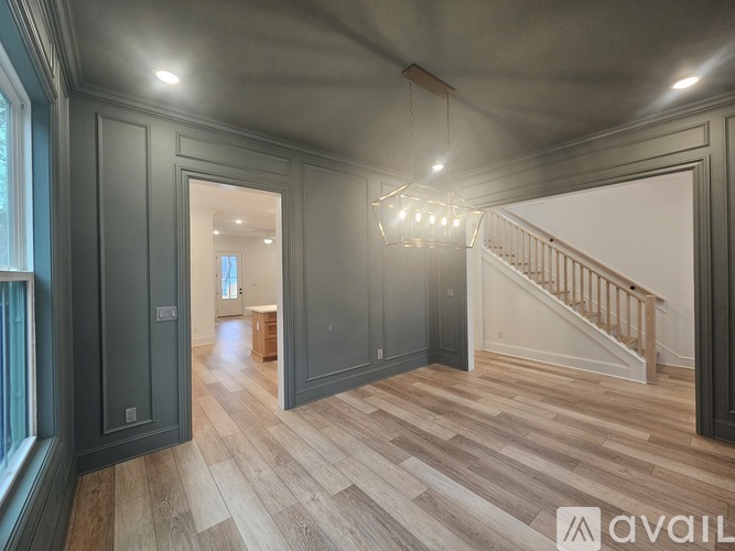 A spacious room with wooden flooring and a staircase.