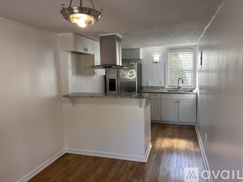 A kitchen with white cabinets and a wooden floor.