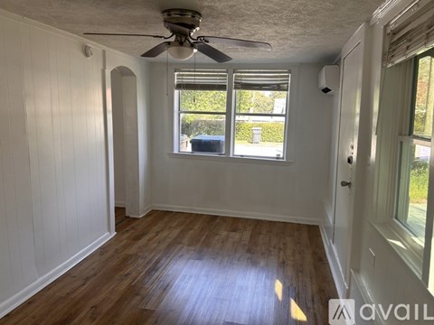 A room with a ceiling fan and wooden flooring.