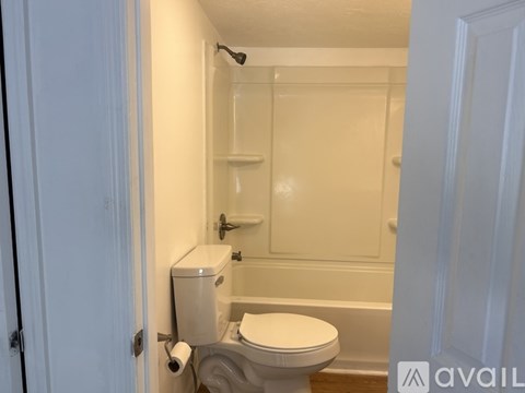 A white toilet with a white towel hanging on the wall.