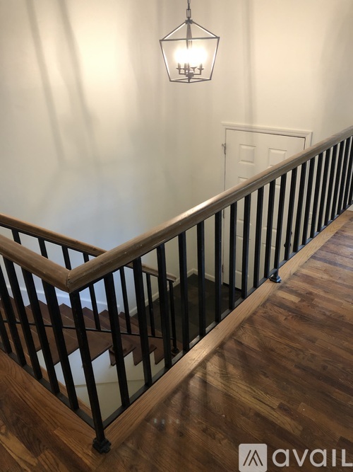 A staircase with a wooden handrail and black balusters.
