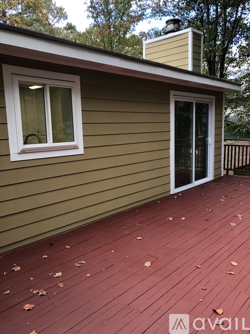 A house with a tan siding and a red deck.