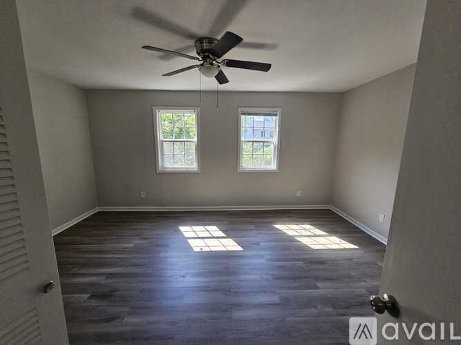 A room with a ceiling fan and two windows.