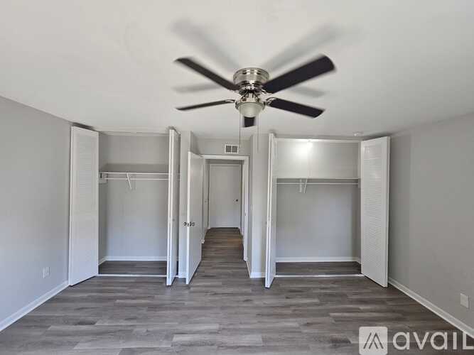 A spacious room with a ceiling fan and open doors leading to other rooms.