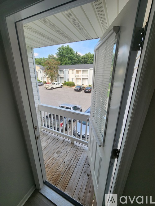 A balcony with a view of a parking lot and apartment buildings.