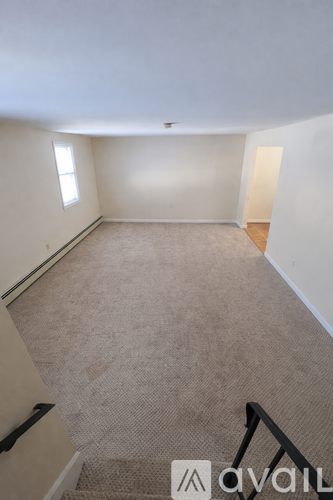 A carpeted room with a staircase leading to the next level.