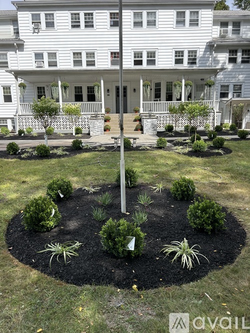 A white house with a circular garden in front.
