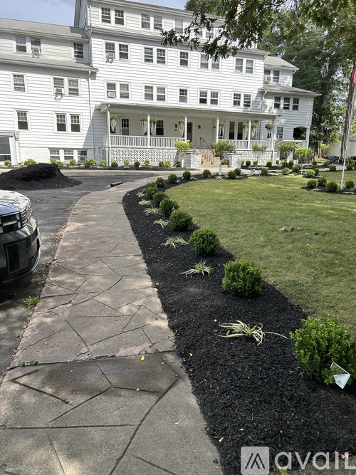 A white house with a black mulched garden bed in front.