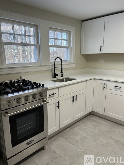 A kitchen with a stove, sink, and cabinets.