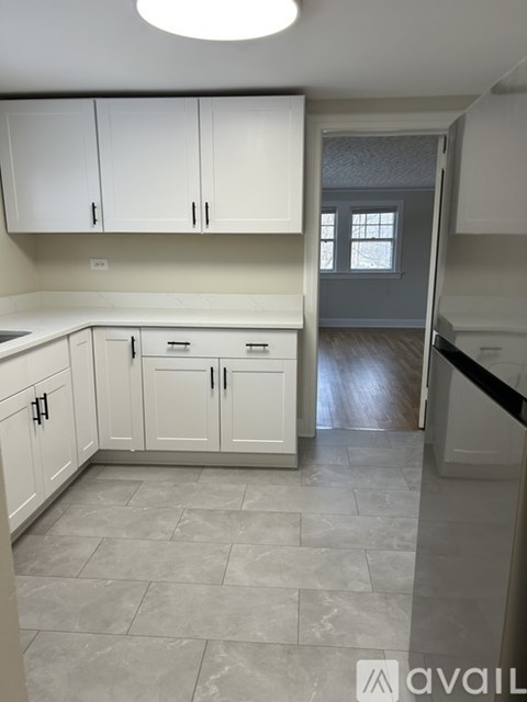 A kitchen with white cabinets and a tiled floor.