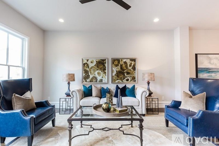 A living room with a blue couch and a glass coffee table.