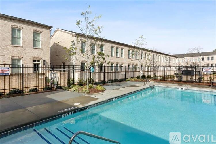 A pool surrounded by a black fence and a building in the background.