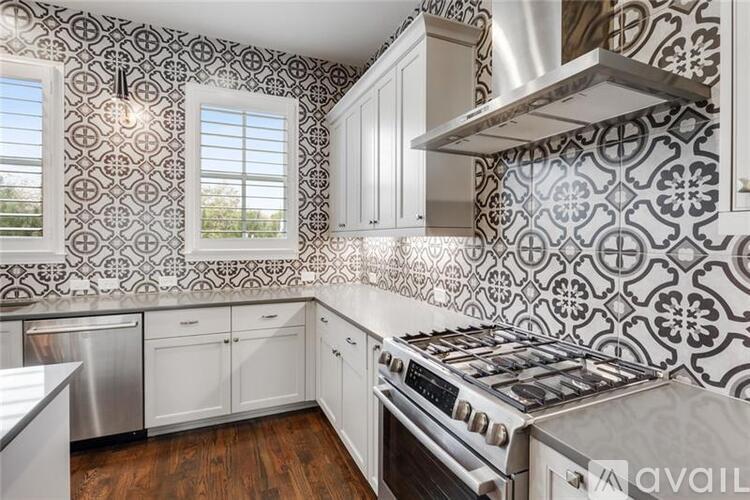 A kitchen with a stove top oven and a backsplash with a black and white pattern.