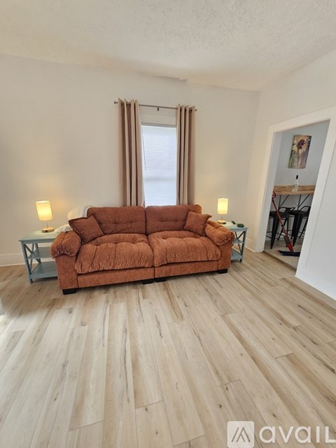 A living room with a brown couch and wooden flooring.