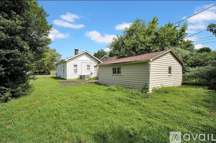 Two houses are situated in a grassy area with trees in the background.