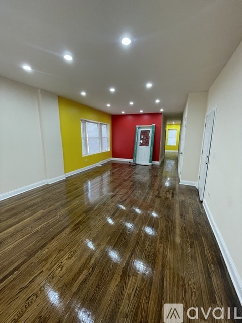 A room with wooden flooring and a red door.