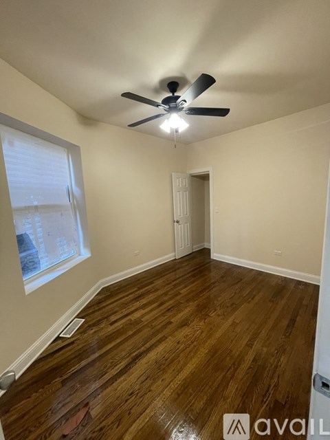 A room with a ceiling fan and wooden flooring.