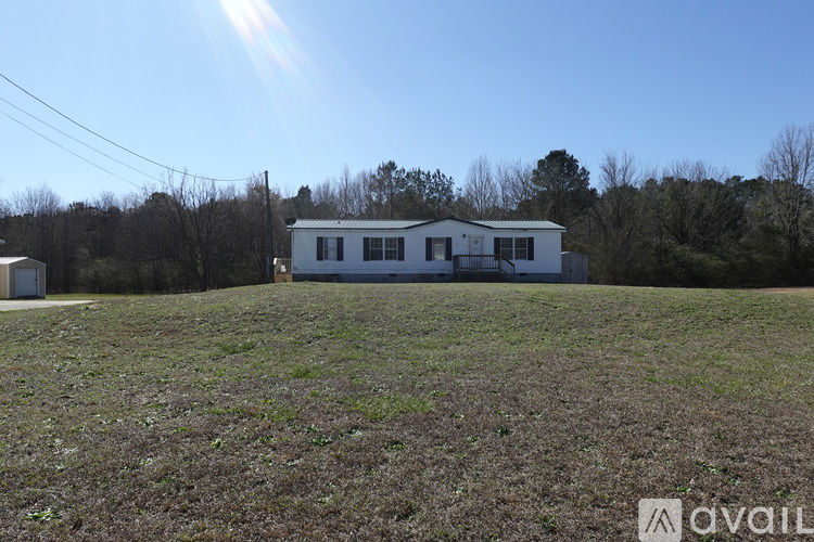 A house is situated in a field with trees in the background.