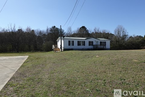 A white house with a brown door is situated in a grassy field.