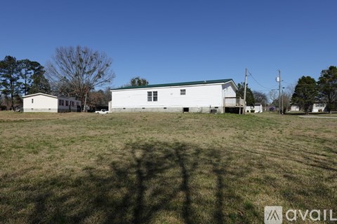 A white house with a green roof is situated in a grassy field.