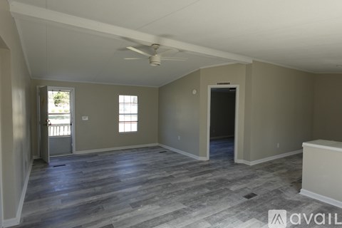 A spacious room with a ceiling fan and wooden flooring.
