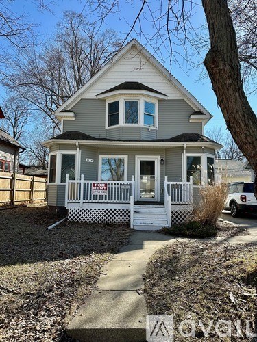 A small house with a porch and a white fence.