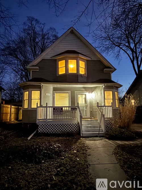 A house with a porch and a sign that says "FOR RENT".