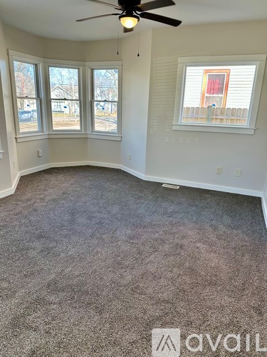 A room with a ceiling fan and carpeted floor.