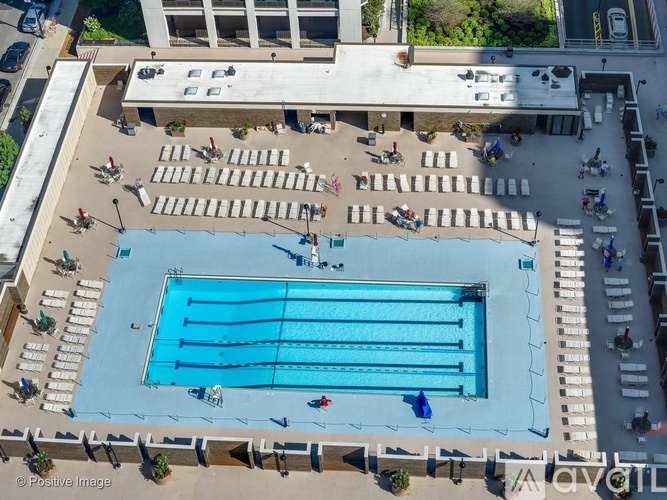 An aerial view of a swimming pool surrounded by lounge chairs and people.