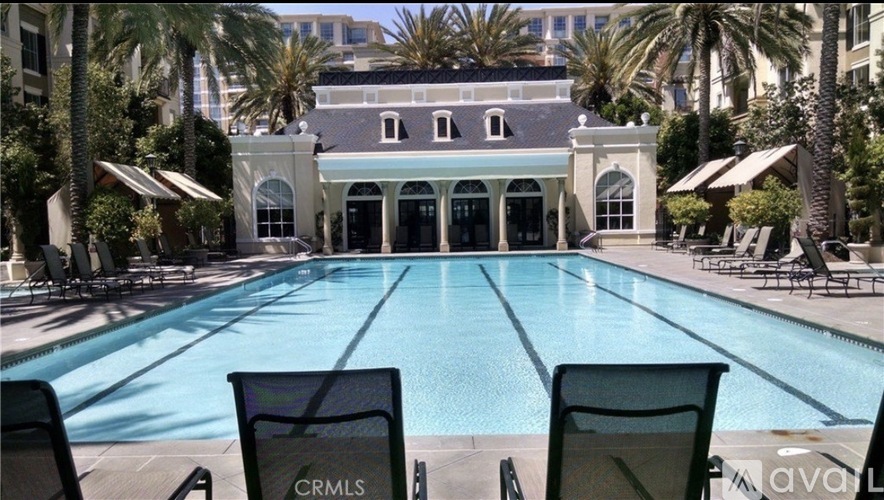 A pool with chairs and a building in the background.