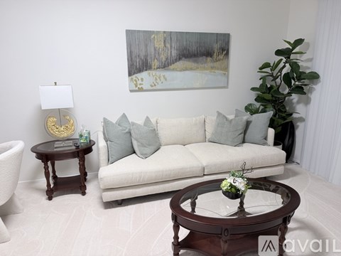 A living room with a white couch, a coffee table, and a painting on the wall.