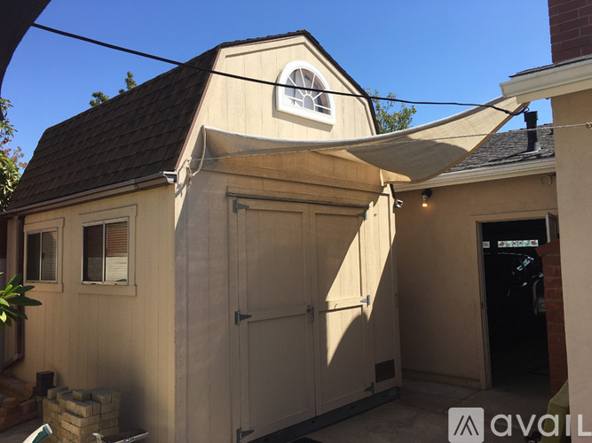 A small building with a brown roof and a white door is available for rent.