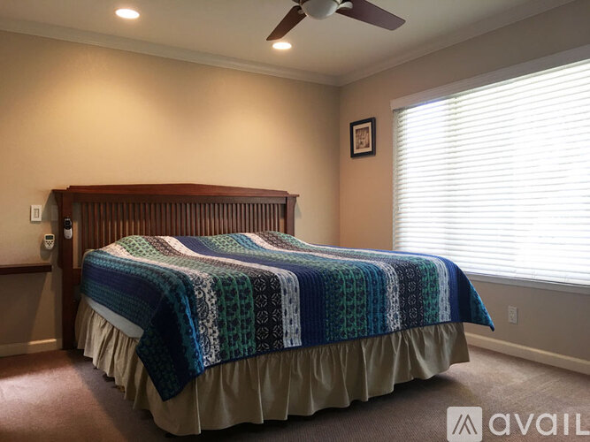 A bedroom with a bed covered in a blue and green patterned blanket.
