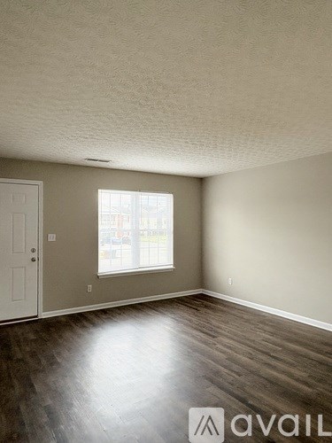 A room with a white door and a window with a view of a street.