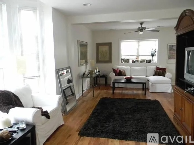 A living room with a black rug and white furniture.
