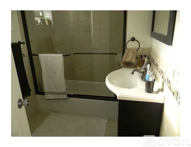 A bathroom with a white sink and a black towel hanging on the door.