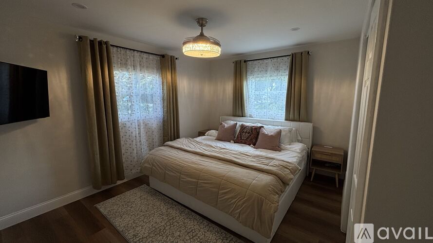 A bedroom with a large bed and a flat-screen TV mounted on the wall.