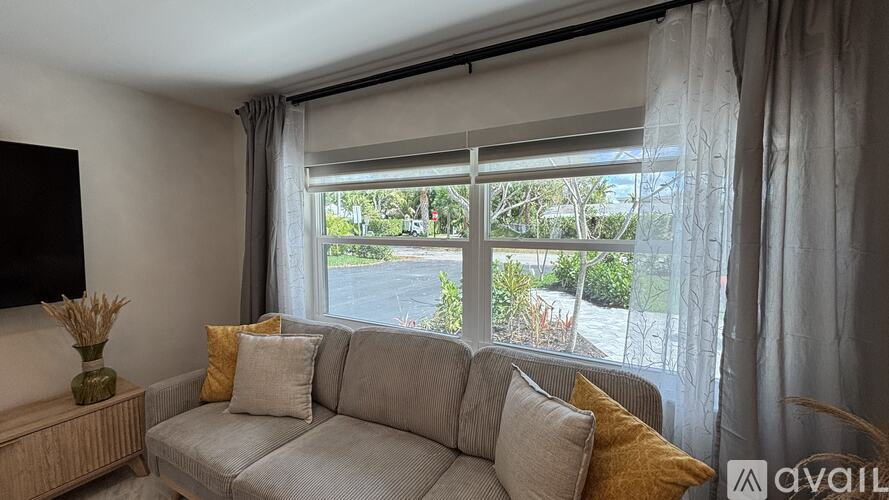 A living room with a grey couch and a window with curtains.