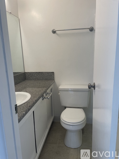 A small bathroom with a toilet, sink, and a grab bar.