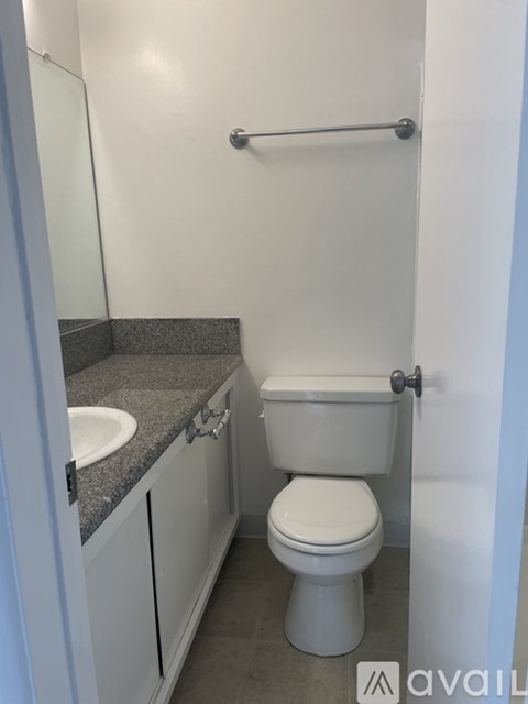 A small bathroom with a toilet, sink, and a grab bar.