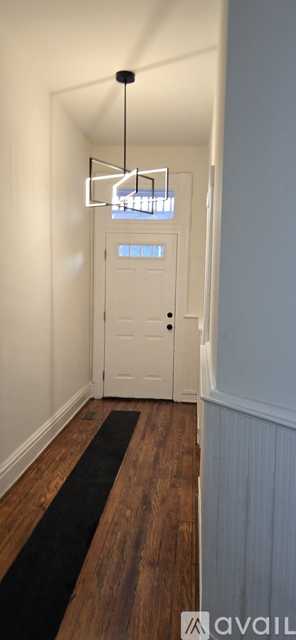 A hallway with a white door and a black mat on the floor.