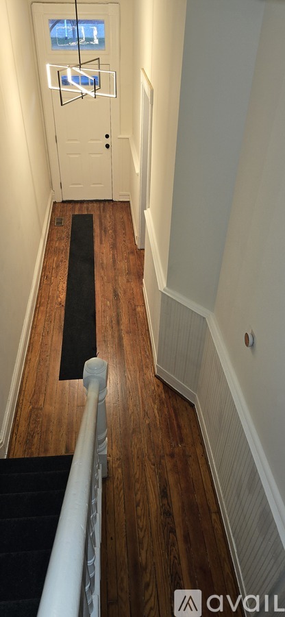 A hallway with a black carpet and wooden floors.